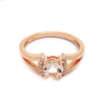 A product photo of a sophisticated pale pink morganite split-band ring with diamond framing sitting on a white background. 4 diamonds sit on either side of the morganite gemstone, with the rose gold split band on either side holding the jewel and diamond arrangement in place.