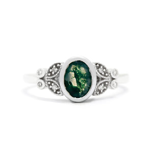 
            
                Load image into Gallery viewer, A product photo of a 9 karat white gold ring sitting on a white background. In the centre sits an impressive, moss agate centre stone - framed by a thick layer of golden bezel. On either side, the plain golden band splits into a flowery pattern of two &amp;quot;petals&amp;quot; and &amp;quot;leaves&amp;quot; each. In the centre of each detail sits a tiny white diamond, to a total of 4. The moss agate stone is semi-opaque white, with stunning natural inclusions within giving the stone a mossy, overgrown appearance.
            
        