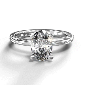 A turntable video of a 14 karat white gold lab diamond solitaire engagement ring sitting in the sun on a white textured background. The brilliant, colourless 1 carat oval-cut diamond measures 8.4mm lengthwise, and is held in place by 4 delicate claws in a prong setting.