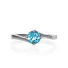 A product photo of a curved-band silver solitaire ring with a bright blue Blue Topaz centre stone sitting on a white background.