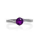 A product photo of a curved-band silver solitaire ring with a deep purple amethyst centre stone sitting on a white background.