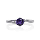 A product photo of a curved-band silver solitaire ring with a midnight blue iolite centre stone sitting on a white background. The deep blue gemstone colour would be a good sapphire substitute.