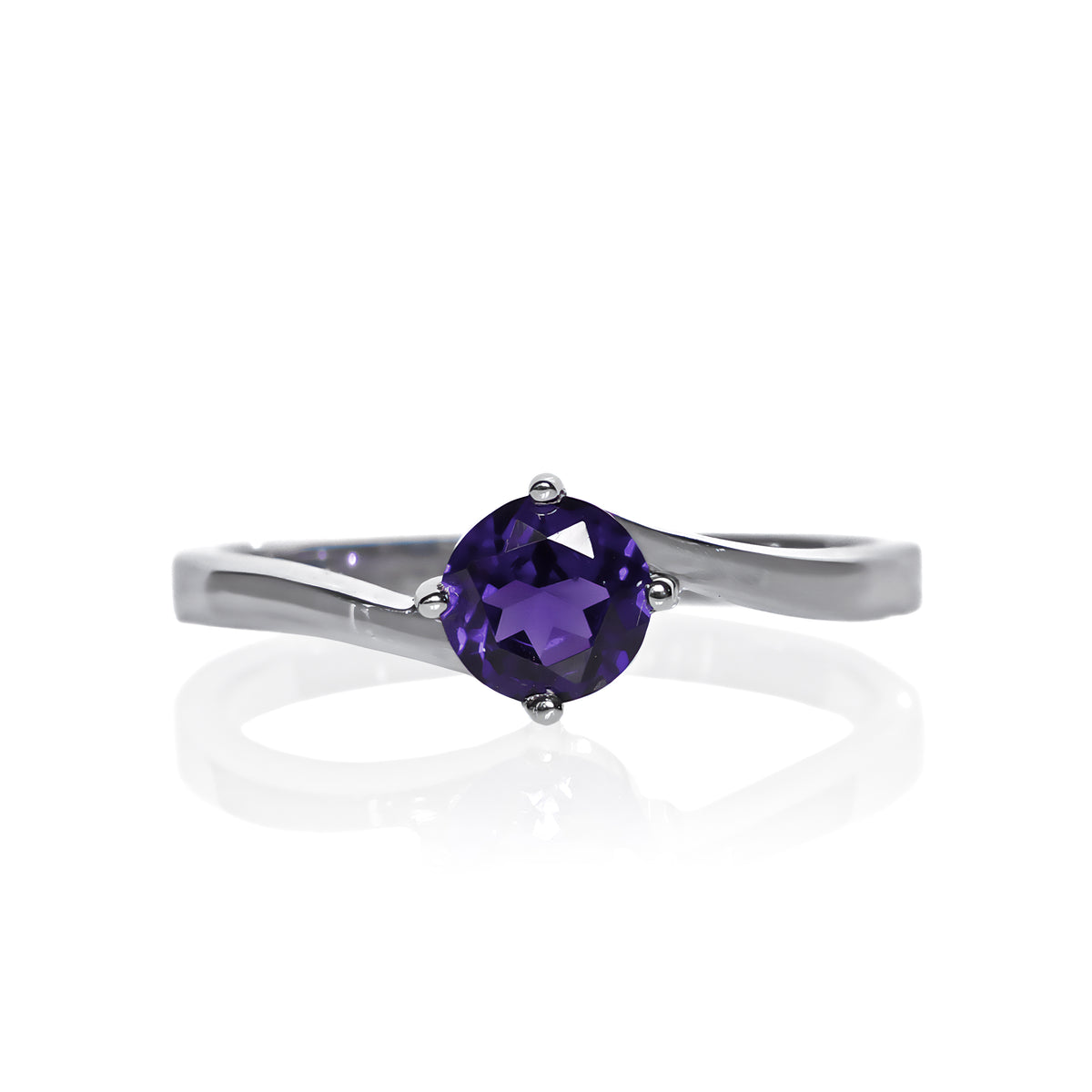 A product photo of a curved-band silver solitaire ring with a midnight blue iolite centre stone sitting on a white background. The deep blue gemstone colour would be a good sapphire substitute.