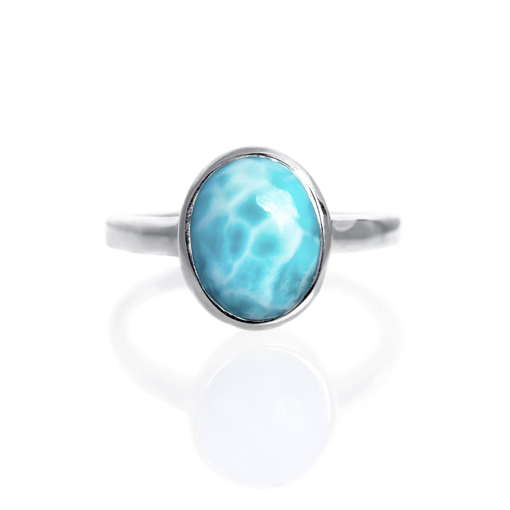 
            
                Load image into Gallery viewer, A product photo of a silver Larimar ring on a white background. The band is tall and thick. The 10x8mm oval cabochon Larimar stone has dappled white and light blue patterning, similar to water reflections at the bottom of a pool. The stone is set in a thick silver bezel setting.
            
        