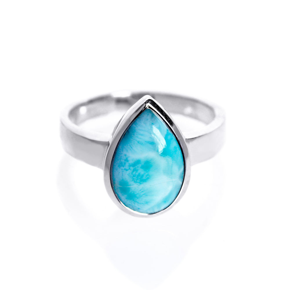 A product photo of a silver Larimar ring on a white background. The band is tall and thick. The 14x9mm pear cabochon Larimar stone has dappled white and light blue patterning, similar to water reflections at the bottom of a pool. The stone is set in a thick silver bezel setting.
