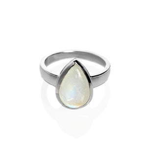 A product photo of a silver moonstone ring on a white background. The band is tall and thick. The 12x8mm pear cabochon moonstone has a blue/purple sheen, with unique milky natural inclusions. The stone is set in a thick silver bezel setting. 