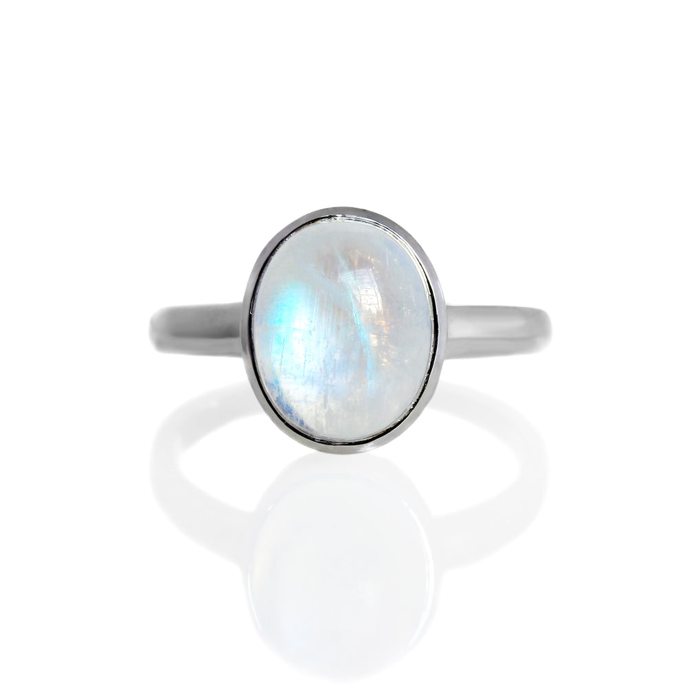 
            
                Load image into Gallery viewer, A product photo of a silver moonstone ring on a white background. The band is tall and thick. The 10x8mm oval cabochon opal stone is uniquely translucent, with a blue-hued sheen. The stone is set in a thick silver bezel setting. 
            
        