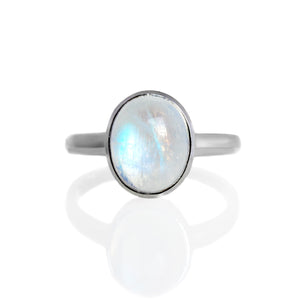 
            
                Load image into Gallery viewer, A product photo of a silver moonstone ring on a white background. The band is tall and thick. The 10x8mm oval cabochon opal stone is uniquely translucent, with a blue-hued sheen. The stone is set in a thick silver bezel setting. 
            
        