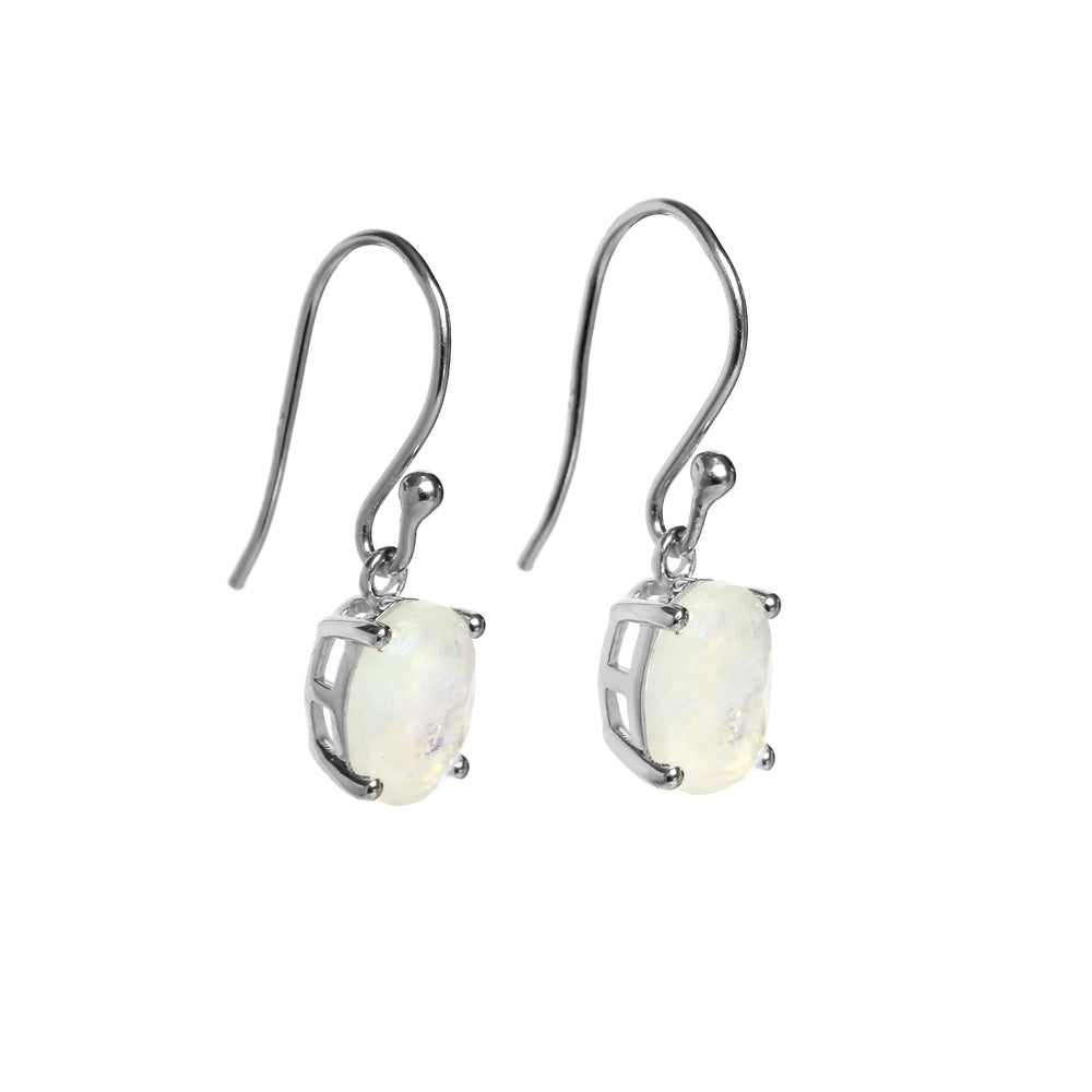 A product photo of a pair of sterling silver natural moonstone drop earrings suspended against a white background. The drop earrings feature shepherd hooks, and the 9x7mm oval-shaped faceted moonstones are held in place by 4 delicate silver claws.