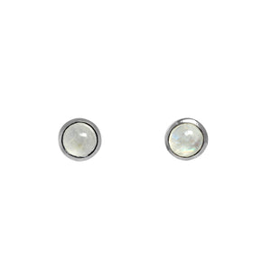 A product photo of a pair of silver moonstone stud earrings sitting against a white background. The 5mm round gemstones have a grey and blue sheen and unique milky inclusions, and are secured in place in bezel settings.
