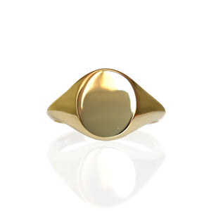 A product photo of a mens' signet ring made of 9k yellow gold on a white background. The face of the ring is an 12x10mm flat ovoid that transitions to a thick rounded band.