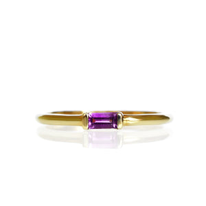 A product photo of a solid 9 karat yellow gold amethyst ring on a white background. The slim golden band is comfortably rounded, and the 4x2mm rectangular purple amethyst stone is held horizontally in place by one squared setting on either side.