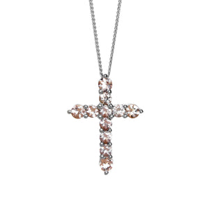 A product photo of a white gold cross pendant delicately bejewelled with pale pink morganite gemstones suspended by a chain against a white background. The Christian cross pendant is made up of 11 stones in total, with the stones at the end of each prong being slightly bigger than the centre jewels.