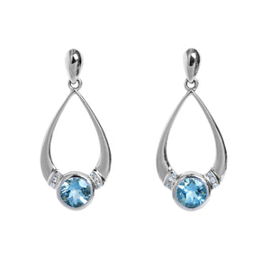 A product photo of a pair of aquamarine stud drop earrings in 9k white gold over a white background. The earrings are composed of a thick frame of white gold in the shape of a tear, swooping downwards to meet on either side of a gold-encased round aquamarine gemstone. Where the frame and bezel-setting meet are 3 dainty detailing diamonds on either side.