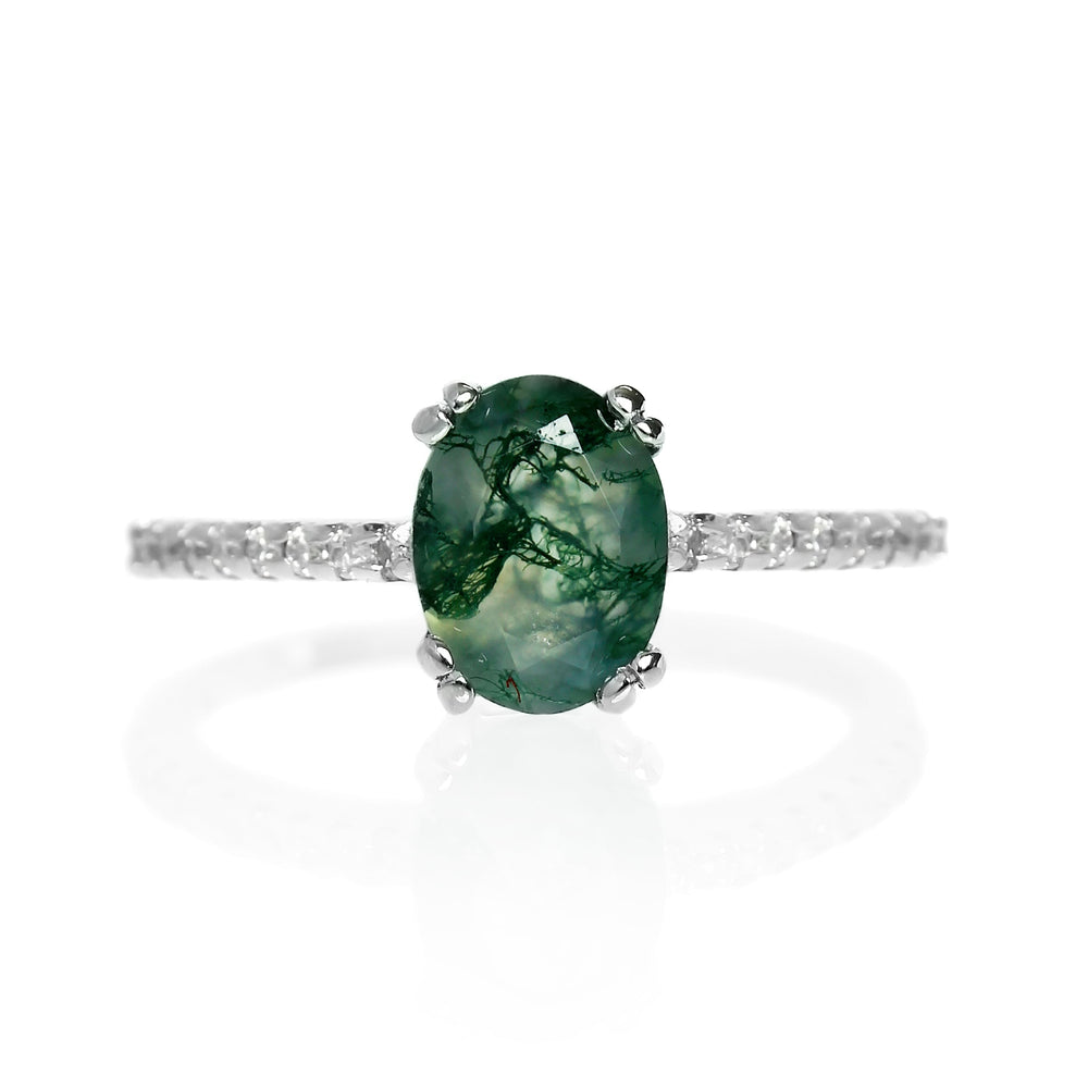 A product photo of a silver moss agate engagement ring on a white background. The ring draws from contemporary alternative styling with the 8x6mm moss agate centre stone, while calling back to the pavé engagement styles of the past with its moissanite-embedded band.