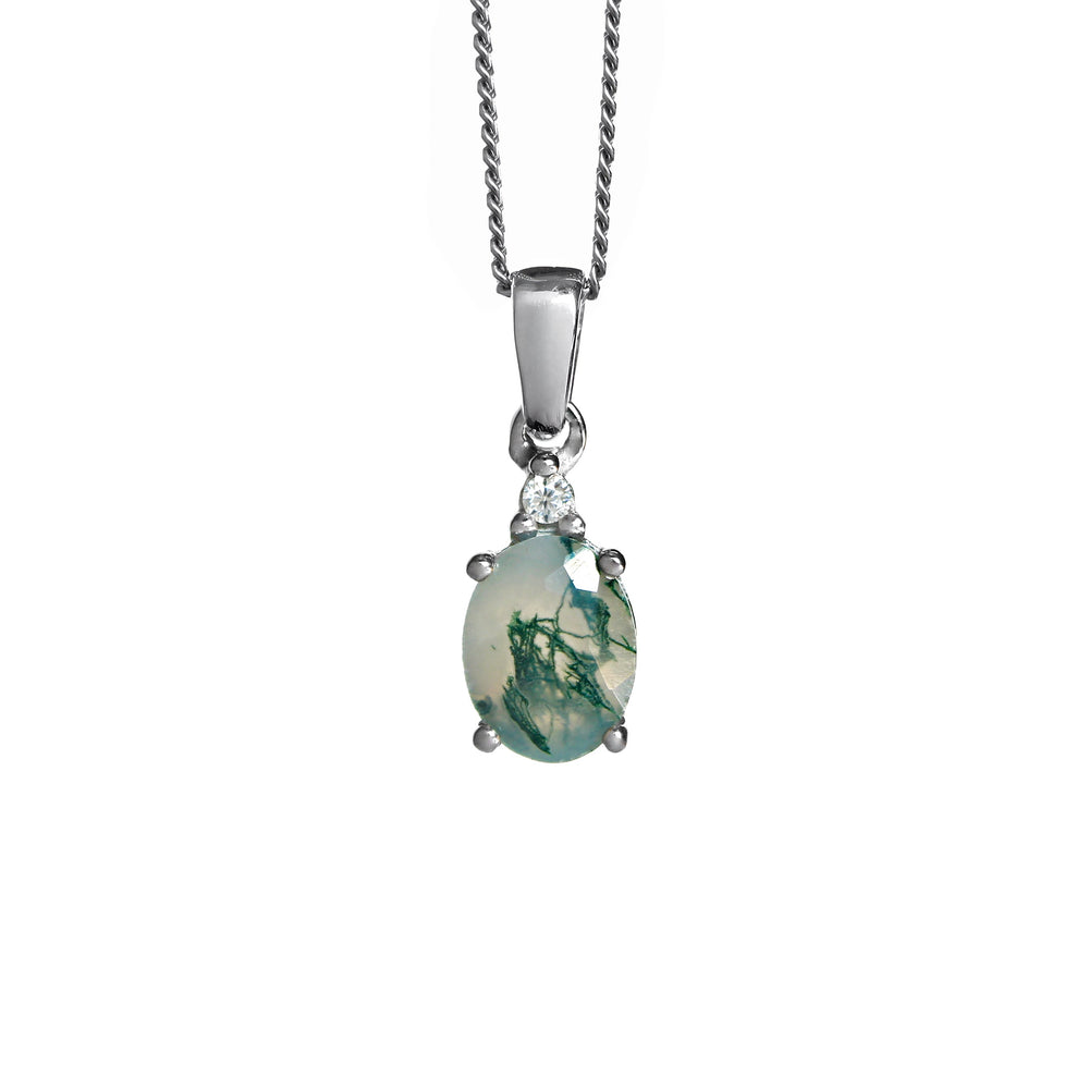 A product photo of a silver moss agate and moissanite necklace suspended against a white background. The beautifully unique moss agate stone is held in place by 4 pairs of claws at its top and bottom, with a singular white moissanite connecting the stone to the rest of the pendant. It is suspended by a simple silver chain.