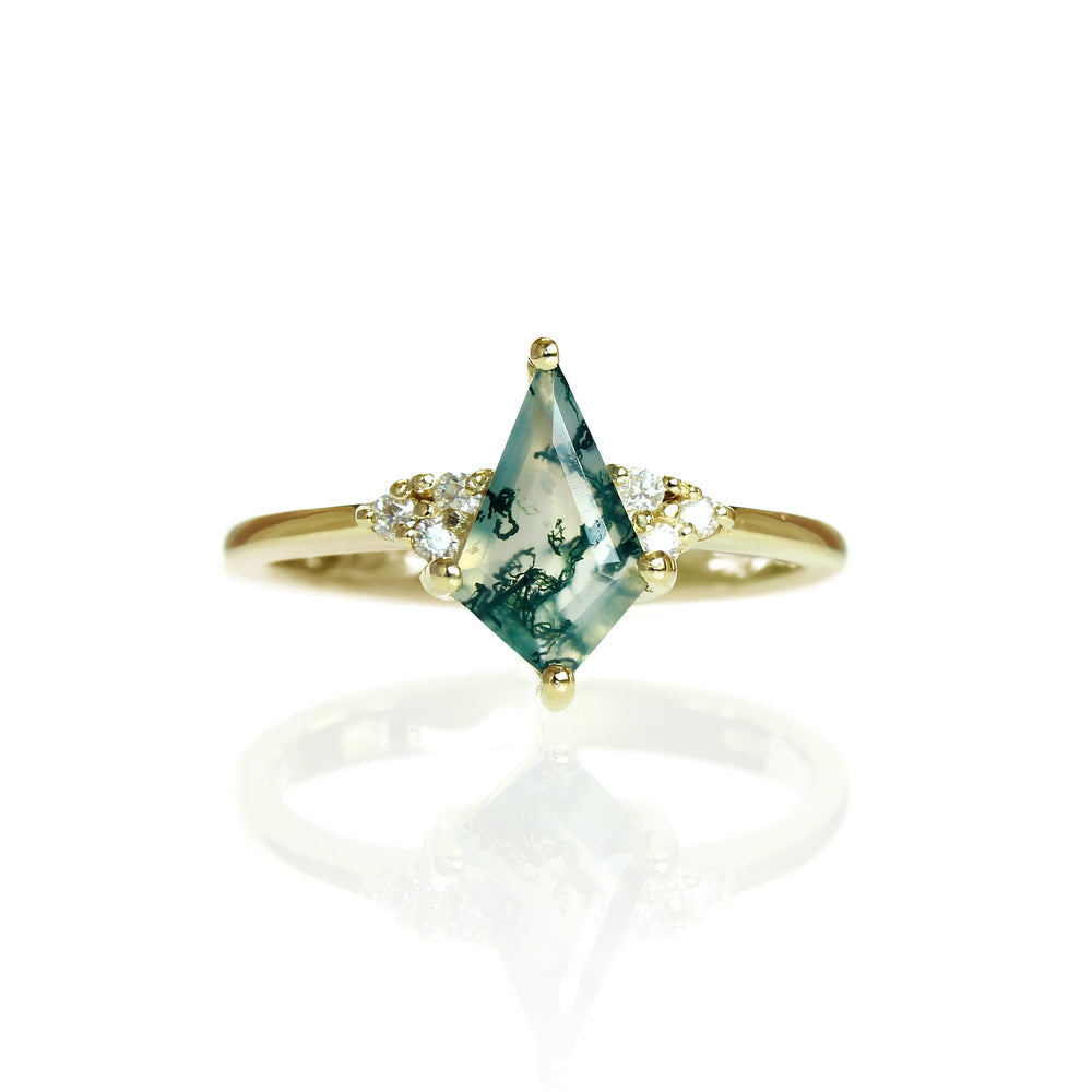 A product photo of a diamond and moss agate engagement ring in solid gold sitting on a white background. The band is smooth and rounded. The 10x6mm kite-shaped faceted moss agate gemstone is embraced on either side by a delicate trio of bright, natural diamonds.