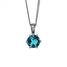 A product photo of a silver London Blue Topaz pendant against a white background. The highly-reflective round cut London Blue Topaz stone is held in place by 6 dainty silver claws. It is suspended by a simple silver chain.