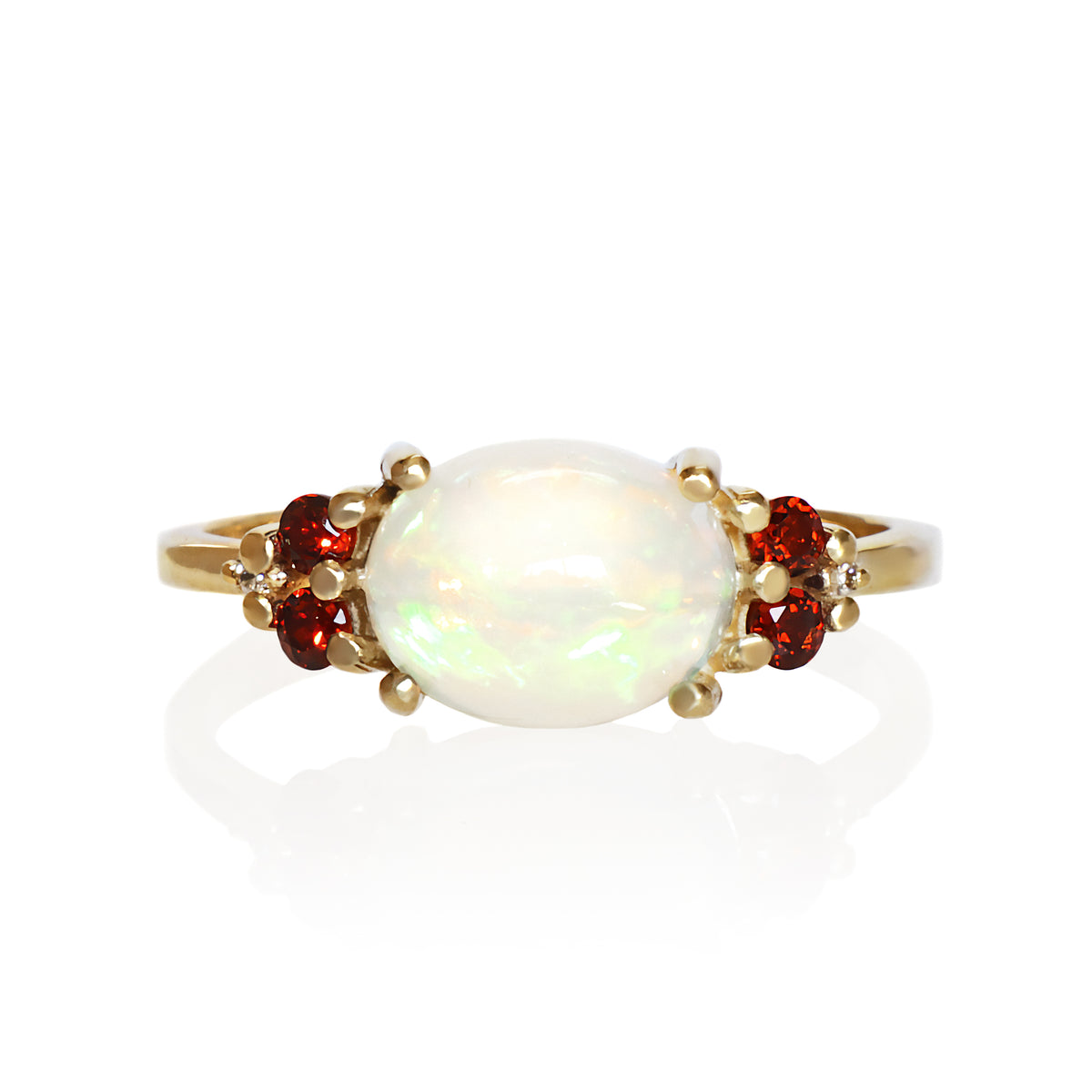 A product photo of a solid 9 carat yellow gold Ethiopian Rainbow Opal and natural diamond/garnet trio cluster ring sitting on a white background. The large oval rainbow opal stands in stark contrast to the little clusters of 2 white sparkling diamond stones on either side.