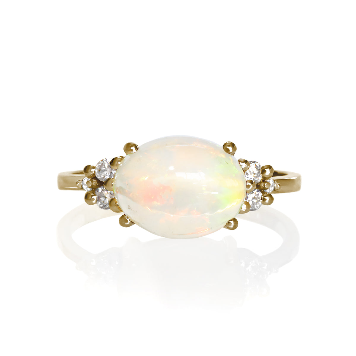A product photo of a solid 9 carat yellow gold Ethiopian Rainbow Opal and natural diamond  trio cluster ring sitting on a white background. The large oval rainbow opal stands in stark contrast to the little clusters of 3 white sparkling diamond stones on either side.