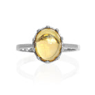 A product photo of a 925 sterling silver citrine birthstone ring sitting on a white background. The fiery orange yellow citrine stone is impressively large, with the cabochon cut allowing the viewer to look into the stone like a crystal ball.  The 10x8mm oval stone is encased in ornate silver detailing, almost like a royal crown.