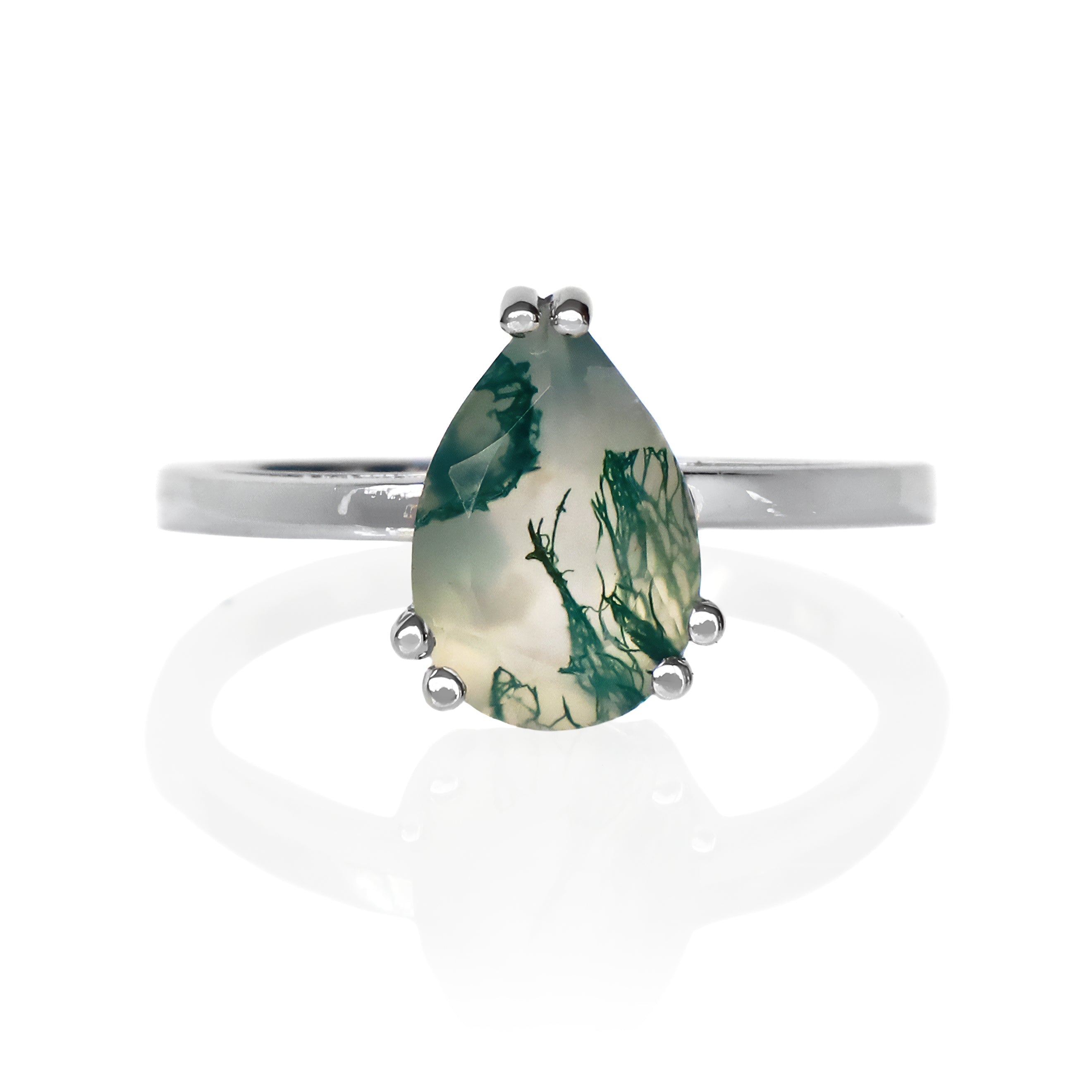 A product photo of a 9k white gold moss agate solitaire ring sitting on a white background. The ring showcases a 9x6mm pear-cut moss agate gemstone as its centre stone, held securely by five polished white gold prongs. The ring's band is a smooth, polished, and slender 9k white gold, providing a delicate and classic foundation for the design. The moss agate displays a translucent, milky white to light green base with distinctive deep green dendritic inclusions.