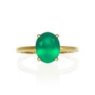 A product photo of an oval 9 karat yellow gold solitaire ring on a white background. The band is rounded and smooth, and the 9x7mm faceted Green Onyx, luminous in the light, is held in place by 4 delicate golden claws.
