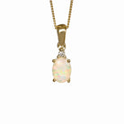 A product photo of a yellow gold hydrophane Ethiopian rainbow opal and diamond necklace sitting against a white background. The beautifully unique rainbow opal stone is held in place by 4 pairs of claws at its top and bottom, with a trio pf delicate white diamonds connecting the stone to the rest of the pendant. It is suspended by a simple yellow gold chain.