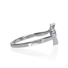 A product photo of a moissanite ring in 9k white gold on a clear white background. A simple crescent band hugs the top and bottom of the 7-jewel cluster of reflective moissanite gems in the centre.