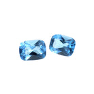 A pair of loose cushion-cut Swiss blue topaz gemstones sitting on a white background. The stones are elaborately faceted, showing off the vibrant blue colouring and fire throughout. The stones would be perfect for use in a bespoke custom-designed pair of earrings, or as a November birthstone pendant and ring set gift.