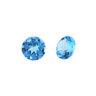 A pair of 7mm round Swiss blue topaz gemstones on a white background. The stones are perfectly-matched in both size and vibrant blue hue, and are ideal for use in a bespoke pair of birthstone earrings, or as a gift to two people with a November birthday.