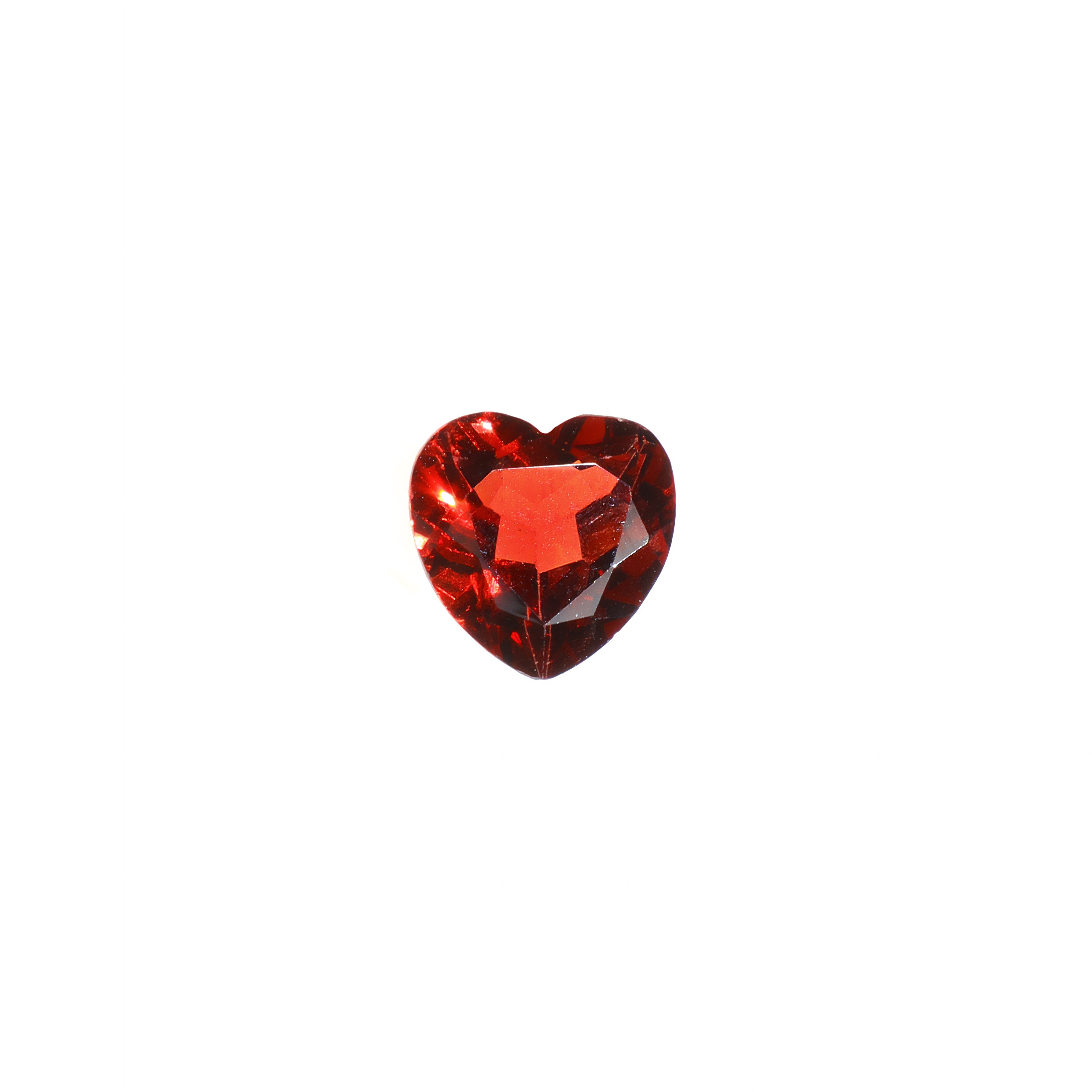A delicate heart-shaped red Mozambican garnet birthstone sitting on a white background. The deep scarlet red stone is dainty and elaborately cut into the shape of an iconic heart, and would be perfect for use in a Valentines Day or anniversary gift pendant for a loved one born in January.