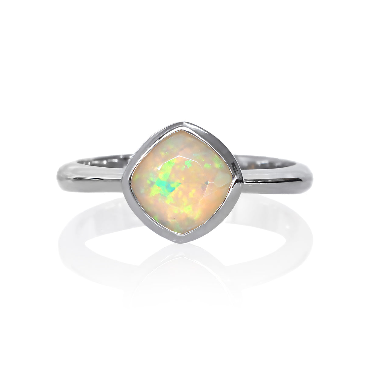 A product photo of a silver ring with a bezel-set ethiopian rainbow opal centre stone sitting on a white background. The silver band is simple and smooth, connecting on either side of a diagonally-oriented squared-cushion ethiopian rainbow opal stone surrounded by a solid frame of silver.