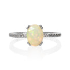 A product photo of a silver Ethiopian rainbow opal engagement ring on a white background. The ring draws from contemporary alternative styling with the 8x6mm Ethiopian rainbow opal centre stone, while calling back to the pavé engagement styles of the past with its moissanite-embedded band.