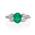 A product photo of an oval green onyx and moissanite ring with floral silver detailing set in solid 925 sterling silver metal. The bold 8x6mm green onyx gemstone is held in place by two petal shapes in filigree silver detailing on either side, each "petal" adorned with a single moissanite in the centre, to a total of 4.