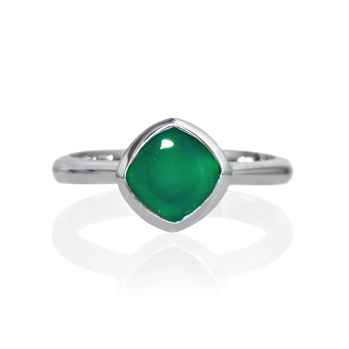 A product photo of a silver ring with a bezel-set green onyx centre stone sitting on a white background. The silver band is simple and smooth, connecting on either side of a diagonally-oriented squared-cushion green onyx stone surrounded by a solid frame of silver.