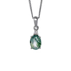 A product photo of a silver moss agate and moissanite necklace suspended against a white background. The beautifully unique moss agate stone is held in place by 4 pairs of claws at its top and bottom, with a singular white moissanite connecting the stone to the rest of the pendant. It is suspended by a simple silver chain.