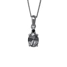 A product photo of a silver tourmalated quartz and moissanite necklace suspended against a white background. The beautifully unique tourmalated quartz stone is held in place by 4 pairs of claws at its top and bottom, with a singular white moissanite connecting the stone to the rest of the pendant. It is suspended by a simple silver chain.