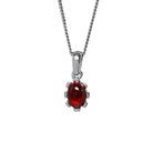 A product photo of a cabochon purple garnet set in solid sterling silver suspended by a silver chain over a white background. The smooth cabochon garnet is framed by flowery sterling silver detailing.