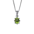 A product photo of a cabochon purple peridot set in solid sterling silver suspended by a silver chain over a white background. The smooth cabochon peridot is framed by flowery sterling silver detailing.