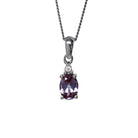 A product photo of a sterling silver lab alexandrite and moissanite necklace sitting against a white background. The beautifully unique lab alexandrite stone is held in place by 4 pairs of claws at its top and bottom, with a single white moissanites connecting the stone to the rest of the pendant. It is suspended by a simple sterling silver chain.