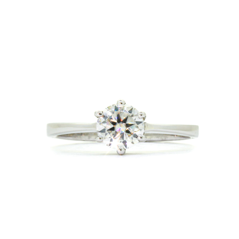 
            
                Load image into Gallery viewer, A product photo of a moissanite ring in 9k white gold sitting on a clear white background. A single reflective moissanite gem sits in the centre of the smooth white gold band, held securely in place by 6 delicate claws.
            
        