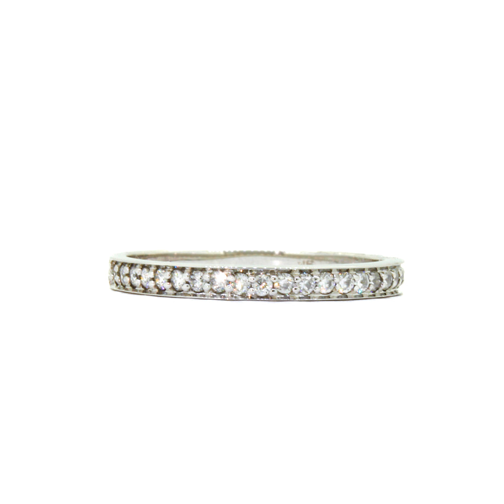 A product photo of a half eternity moissanite ring in 9k white gold sitting on a clear white background. two flat circular bands hug the top and bottom of the central band embedded with dazzling moissanite gems, all the way around.