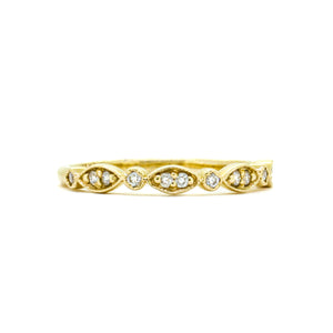A product photo of an ornate moissanite ring in 9k yellow gold. Oval gold frames adorned with two small moissanite gems each alternate with circular gold frames adorned with singular moissanite gems and make up the ring for about half of its length before smoothing out into a simple rounded yellow gold band.