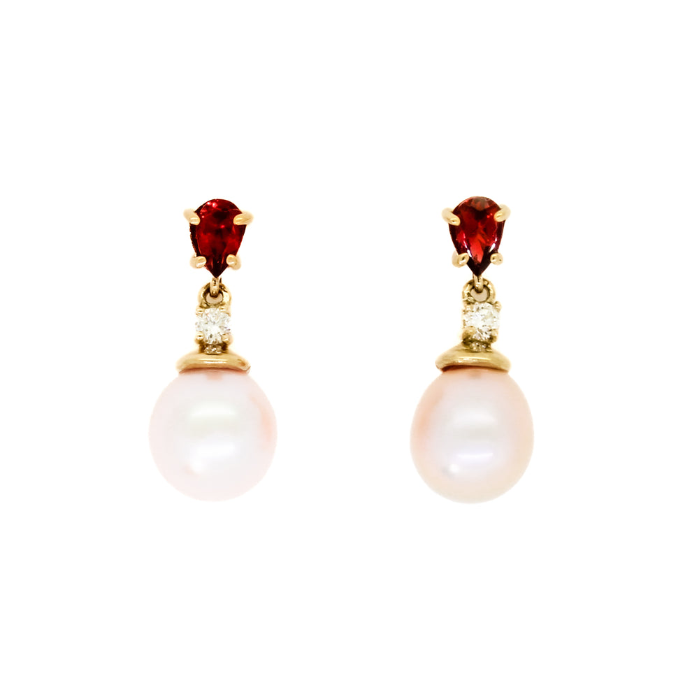 A product photo of delicate rosaline pearl earring studs on a white background. The rosaline pearls each have diamond detailing above them and a pear-shaped garnet gem connecting both to the yellow gold stud.