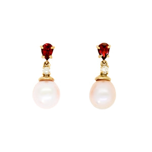 A product photo of delicate rosaline pearl earring studs on a white background. The rosaline pearls each have diamond detailing above them and a pear-shaped garnet gem connecting both to the yellow gold stud.
