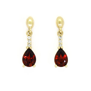 A product photo of 7x5mm Pear Garnet & Diamond Earrings in 9k Yellow Gold sitting on a plain white background. A golden strip connects the garnets to the studs, each strip adorned with 3 diamonds each. The garnets reflect sanguine hues across their multi-faceted edges.