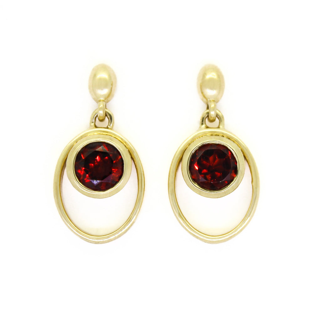 
            
                Load image into Gallery viewer, A product photo of 5.5mm Round Bezel-set Garnet Earring Studs in 9k Yellow Gold sitting on a plain white background. The bezel-set stones are nestled at the top of golden oval loops of similar thickness to the bezel frames. The garnets reflect sanguine hues across their multi-faceted edges.
            
        