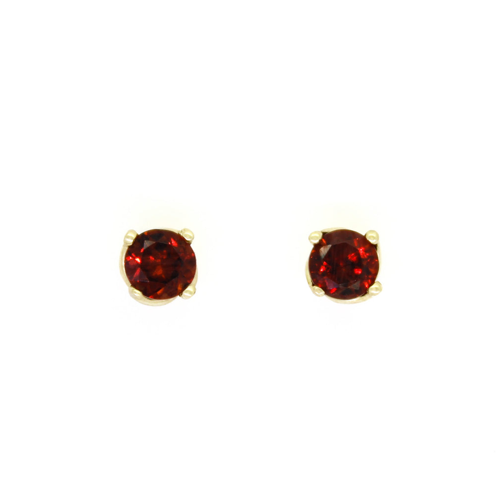 A product photo of 4.5mm Round Garnet Earring Studs in 9k Yellow Gold sitting on a plain white background. The stones are held in place by 4 delicate golden claws arranged in a flower-like pattern where they meet the stud. The garnets reflect sanguine hues across their multi-faceted edges.