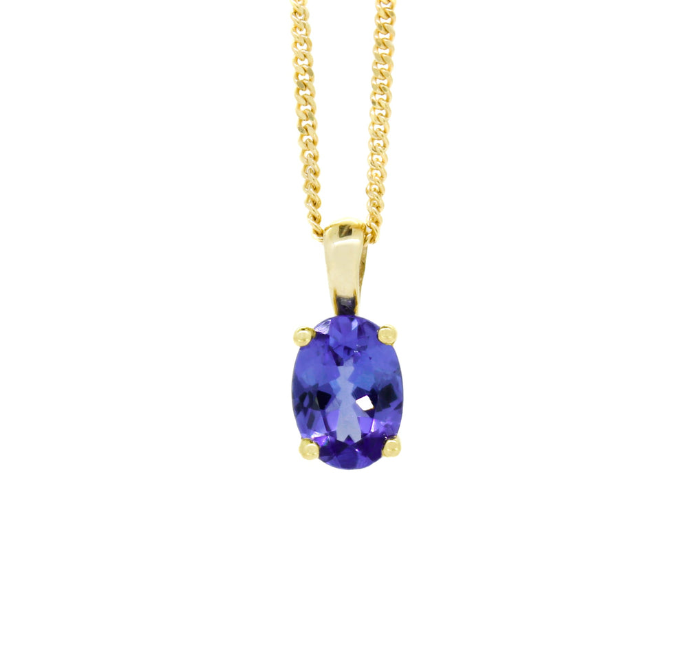 A product photo of a yellow gold tanzanite pendant suspended by a chain against a white background. The oval stone is held in place by 4 small claws, and reflects violet blue and indigo colours from its many edges.